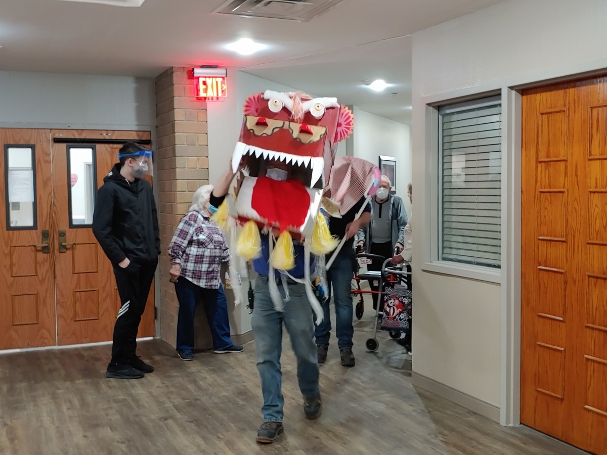 A traditional dragon dance performance takes place indoors, delighting onlookers with vibrant costumes and lively movement.
