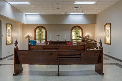 Interior of a religious space featuring a wooden altar and stained glass windows.
