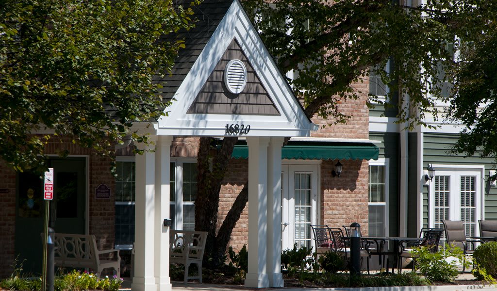 A building entrance featuring an awning and porch, surrounded by trees.