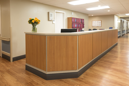 A modern reception desk in a well-lit office environment, adorned with a bouquet of flowers.