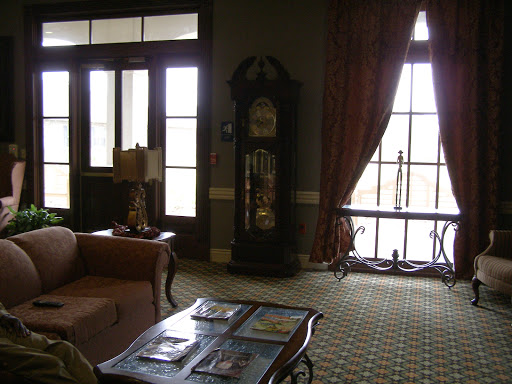 A cozy living room featuring a vintage clock, comfortable seating, and large windows.