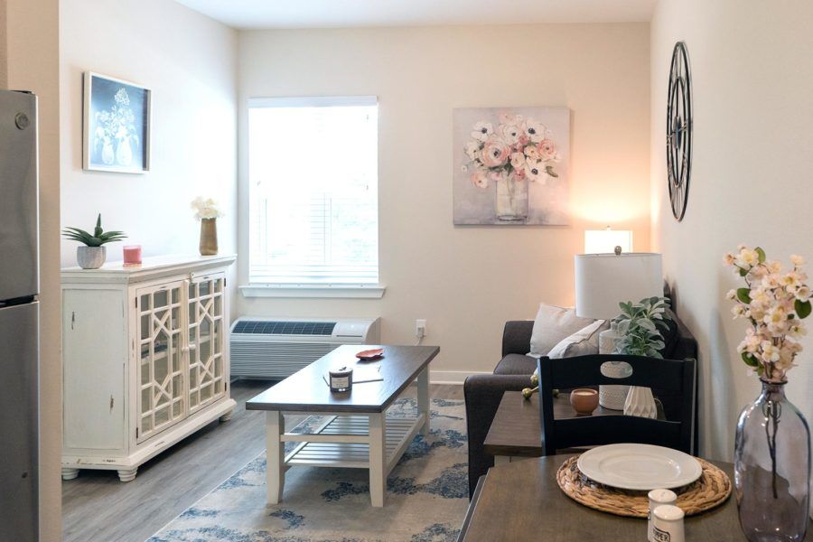 A cozy living room with modern dcor, featuring a sofa, coffee table, artwork, and soft lighting.