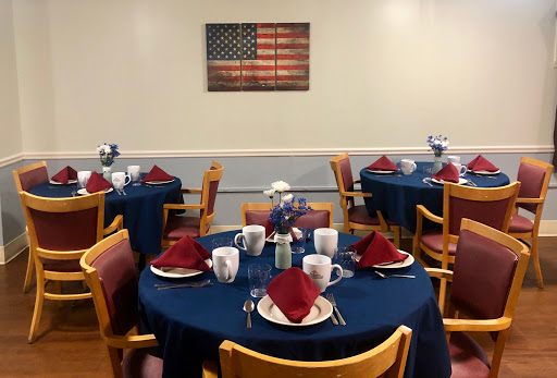 A beautifully arranged dining area featuring tables set with red napkins and coffee mugs, adorned with an American flag artwork.