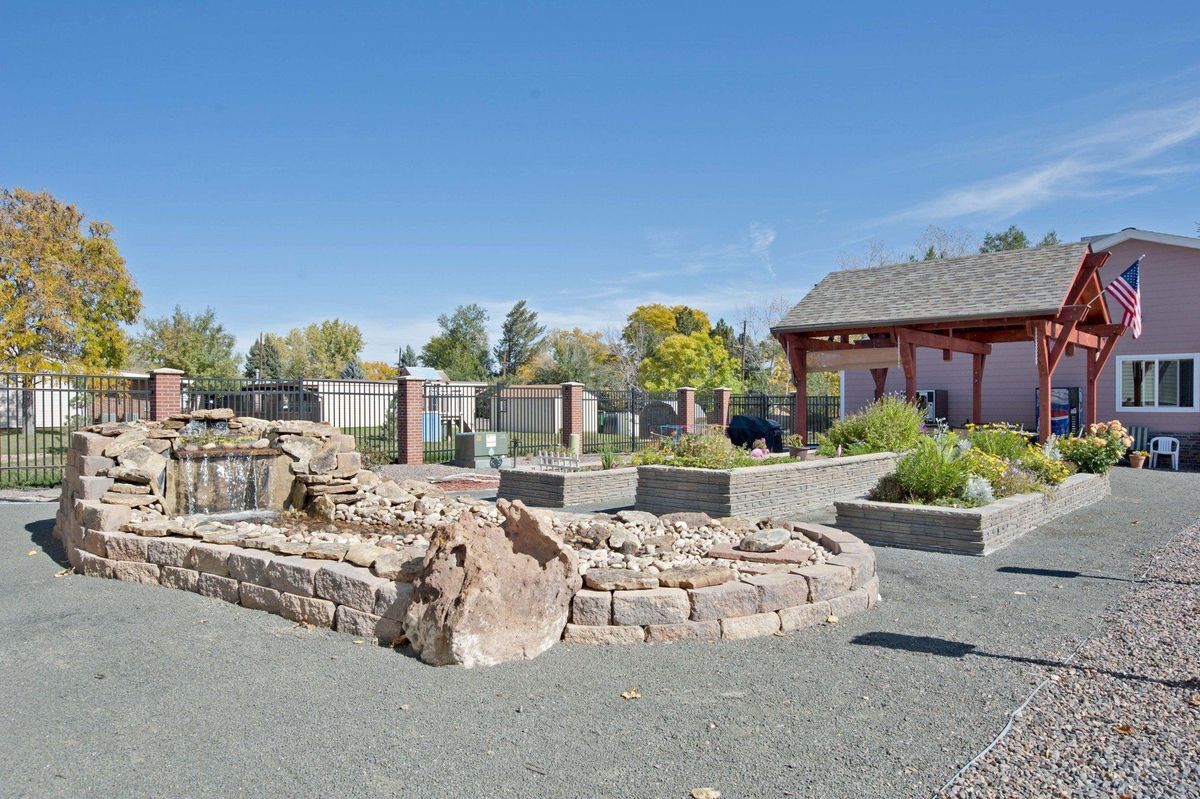 A landscaped garden featuring rock formations, plants, and trees under a clear blue sky.