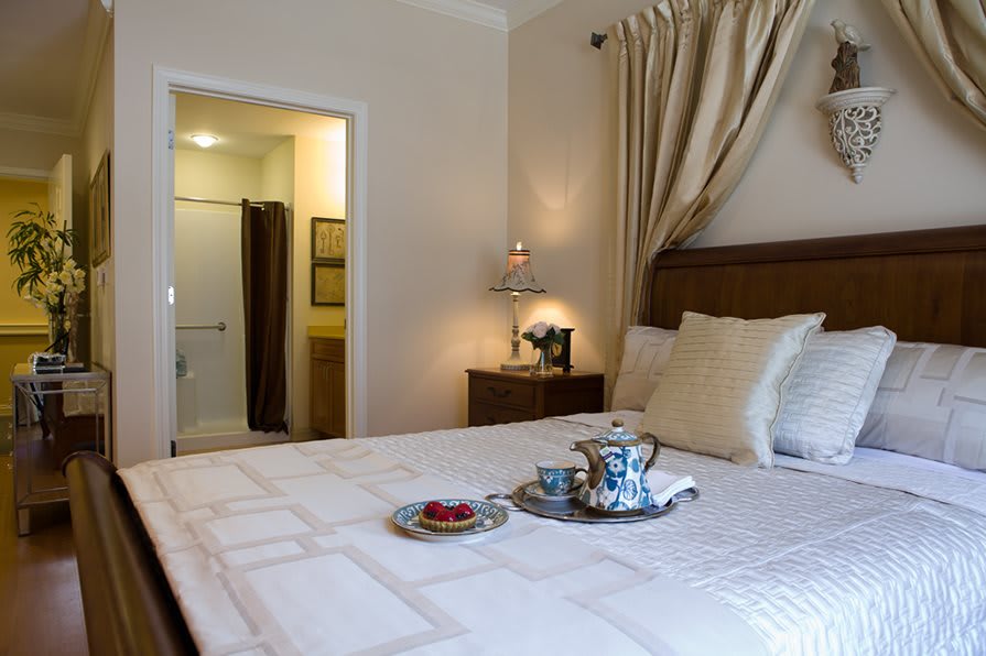 A cozy bedroom with a neatly made bed and a tea set on a tray.
