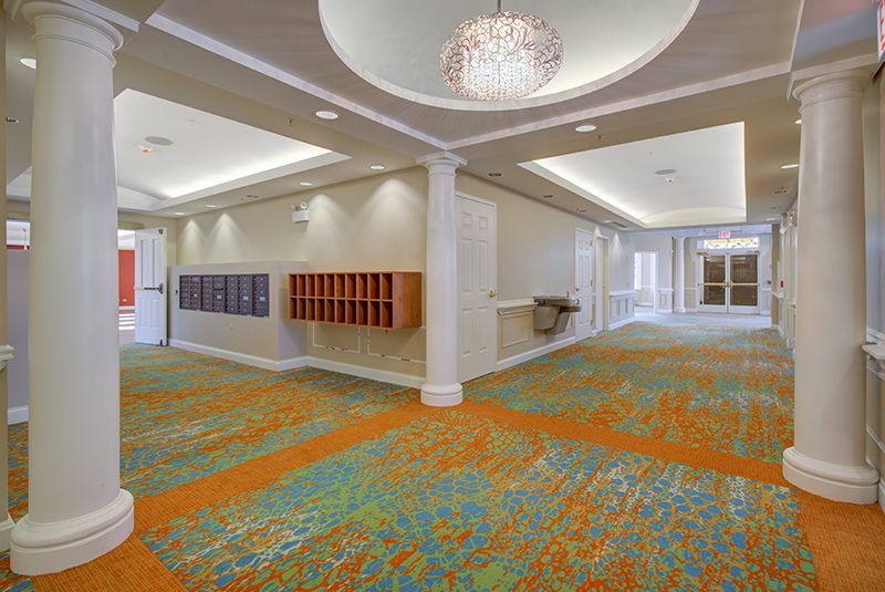 Spacious lobby with colorful carpet and elegant chandelier.