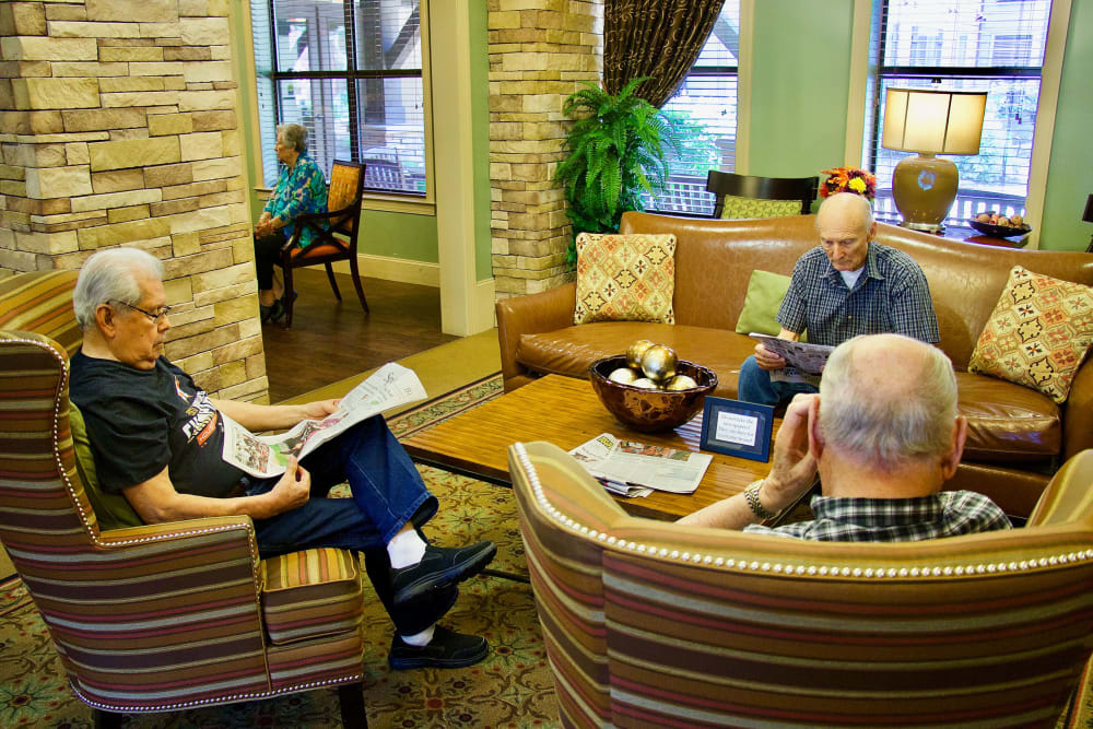 Seniors relaxing and reading in a community lounge area.