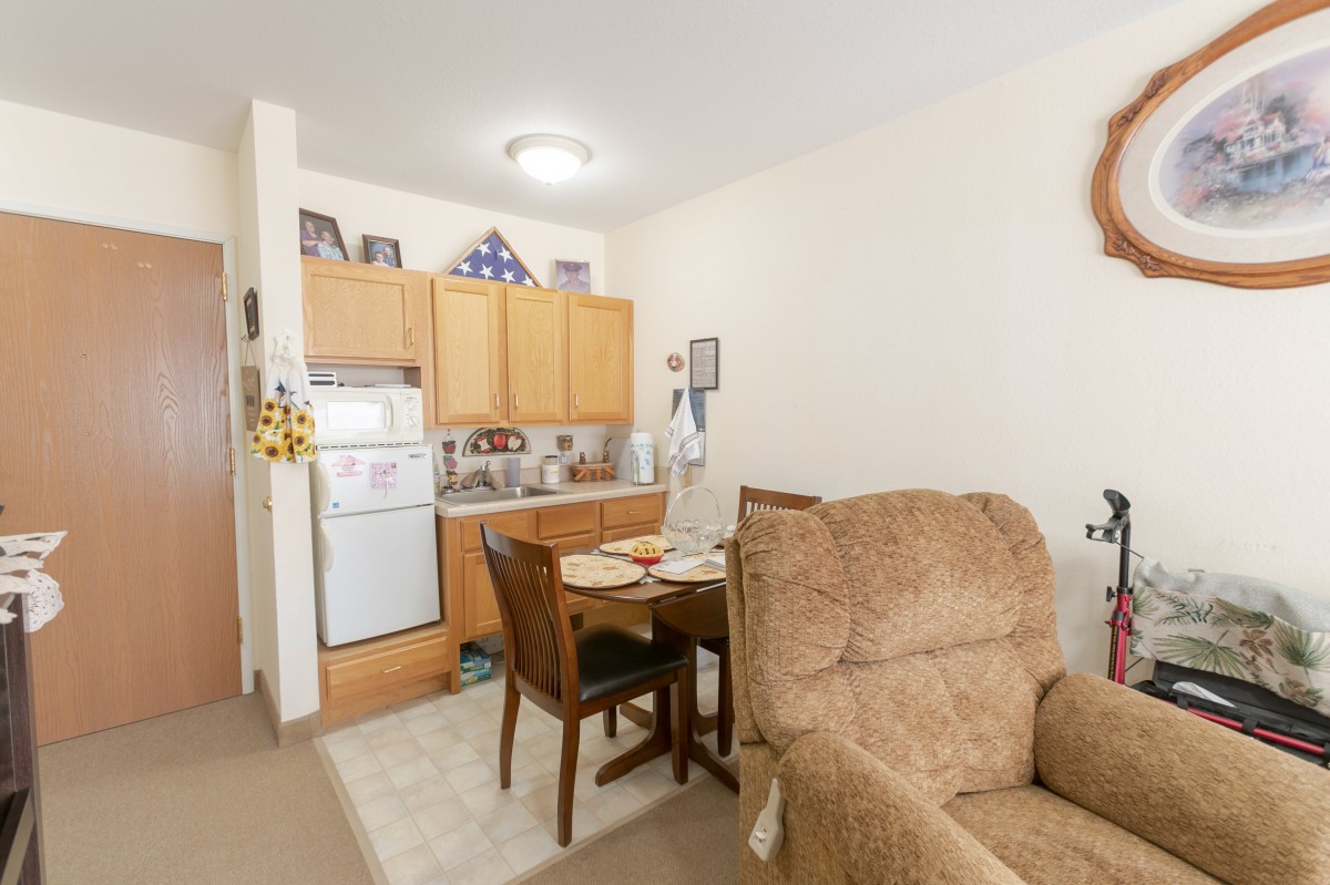 A cozy apartment kitchen and dining area with wooden cabinets and a small table.