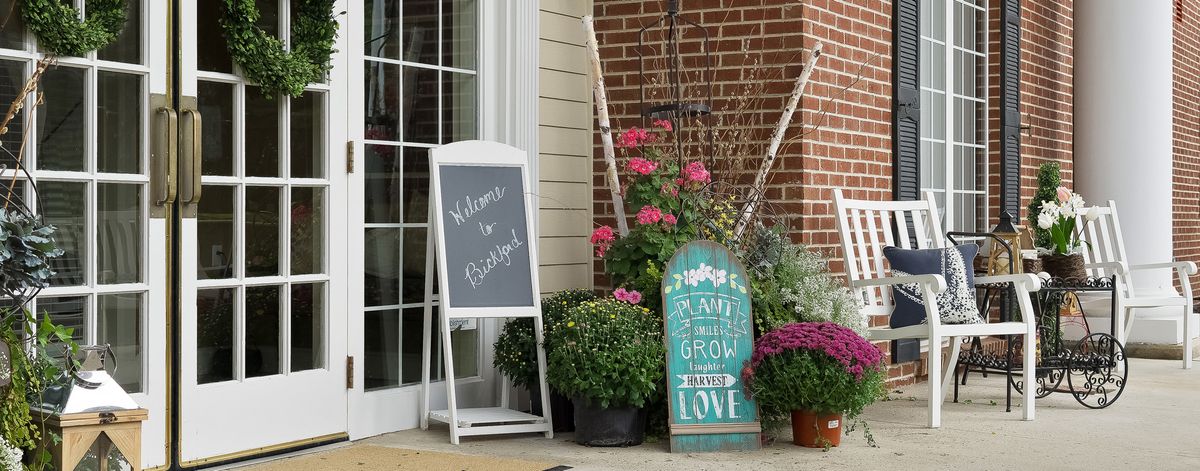 A welcoming outdoor scene with potted plants and charming signage.