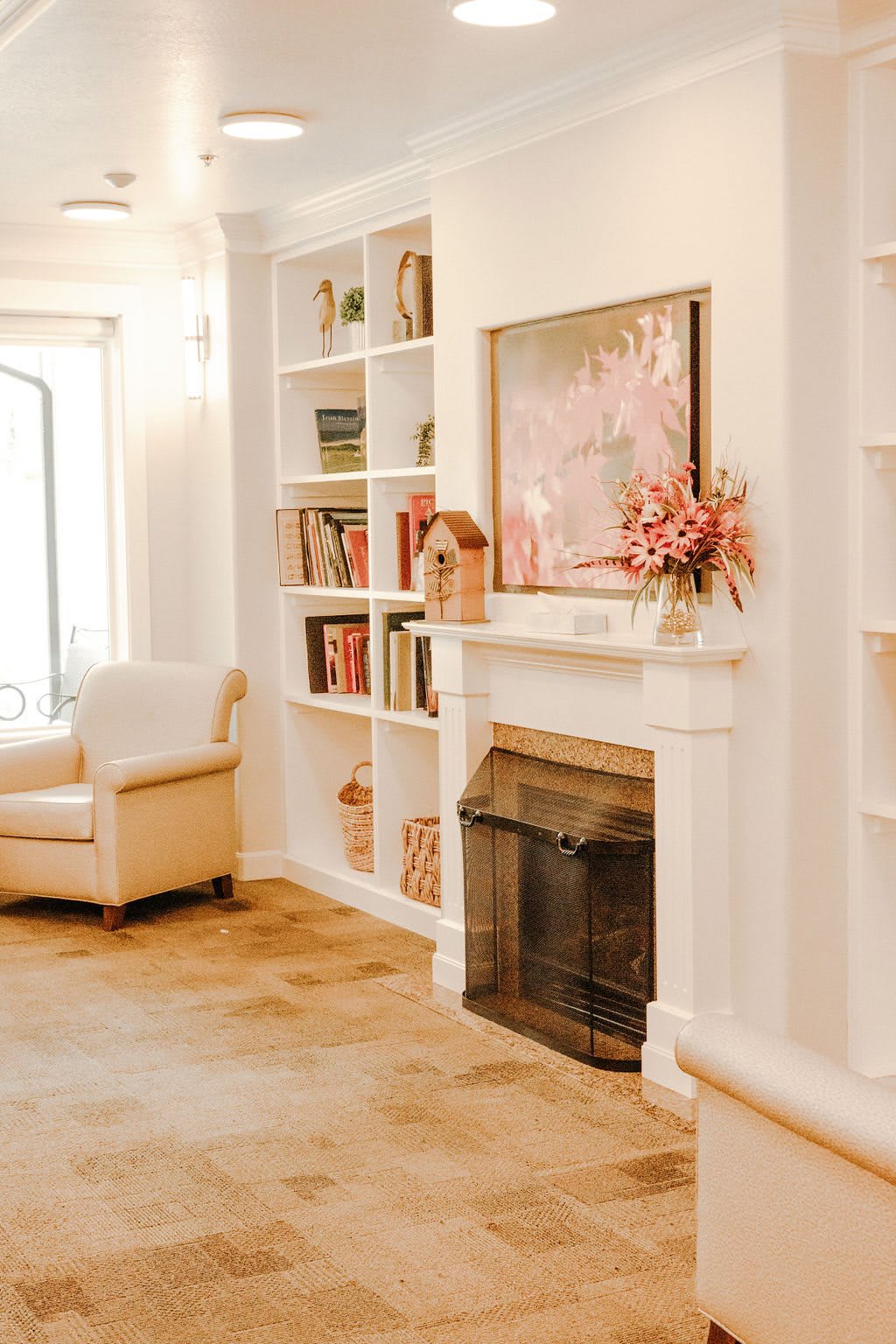 A cozy living room with a fireplace, bookshelves, and an armchair.