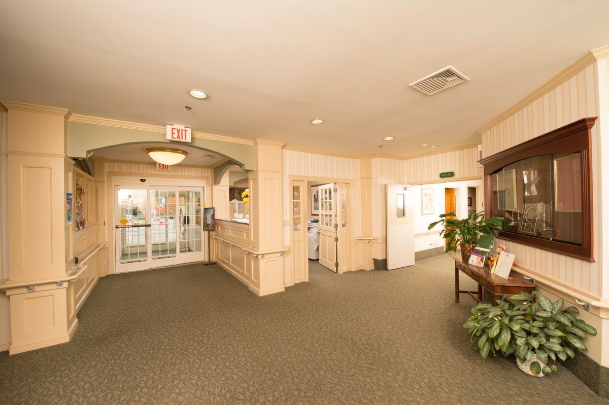 A well-lit hotel lobby with a carpeted floor and a reception area.