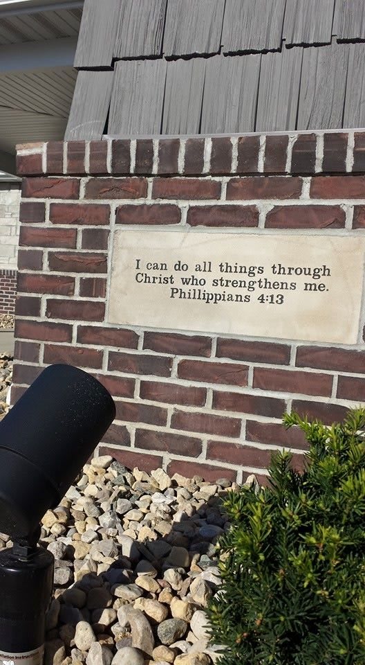 A brick wall with a plaque displaying the Bible verse Philippians 4:13.