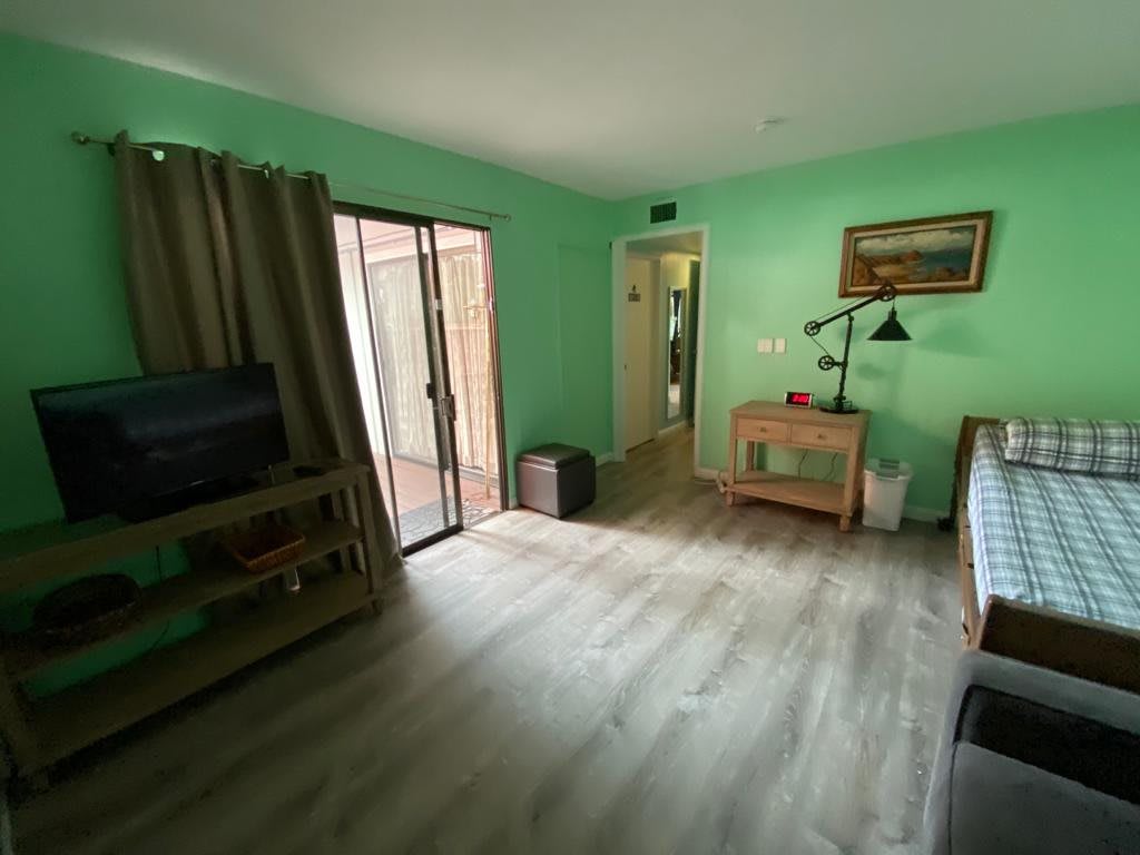 A cozy living room with green walls, a hardwood floor, and sliding doors leading outside.