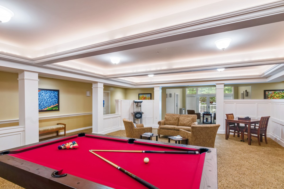 A cozy game room featuring a red pool table and comfortable seating areas.