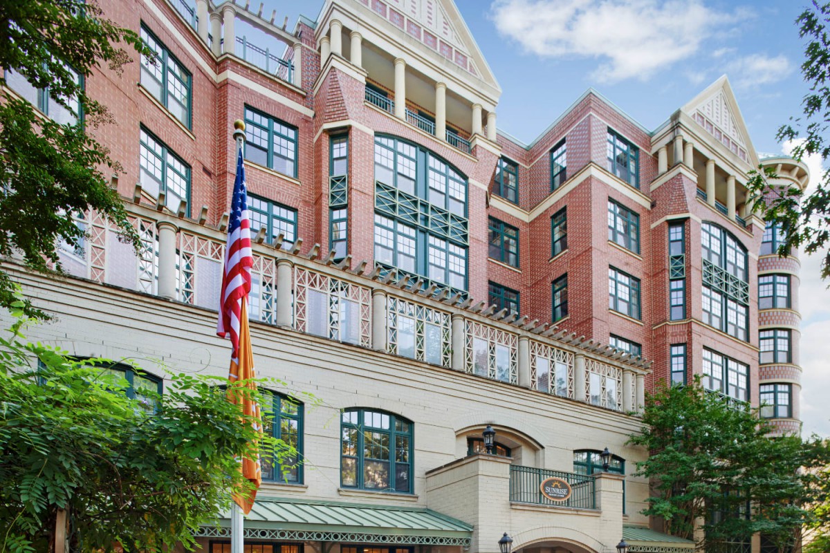 A multi-story brick hotel with large windows and flags displayed outside.