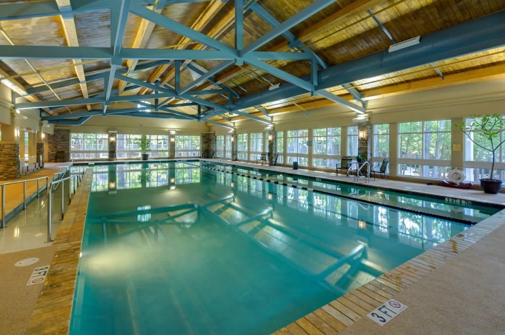 An indoor swimming pool with large windows and exposed ceiling beams.