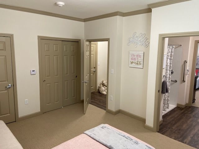 A cozy bedroom with beige walls, featuring a closet and open doors.