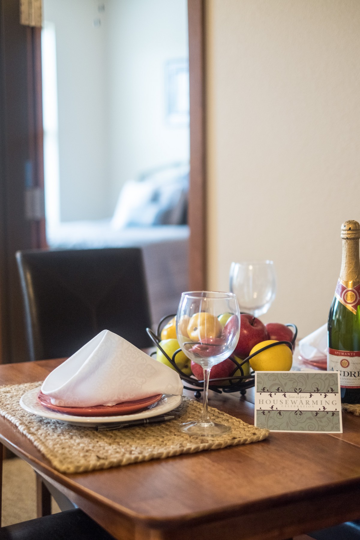 A well-set dining table with a fruit bowl, champagne, and elegant place settings.