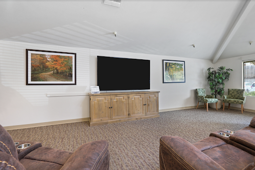 A cozy living room featuring comfortable seating, a large television, and tasteful wall art.