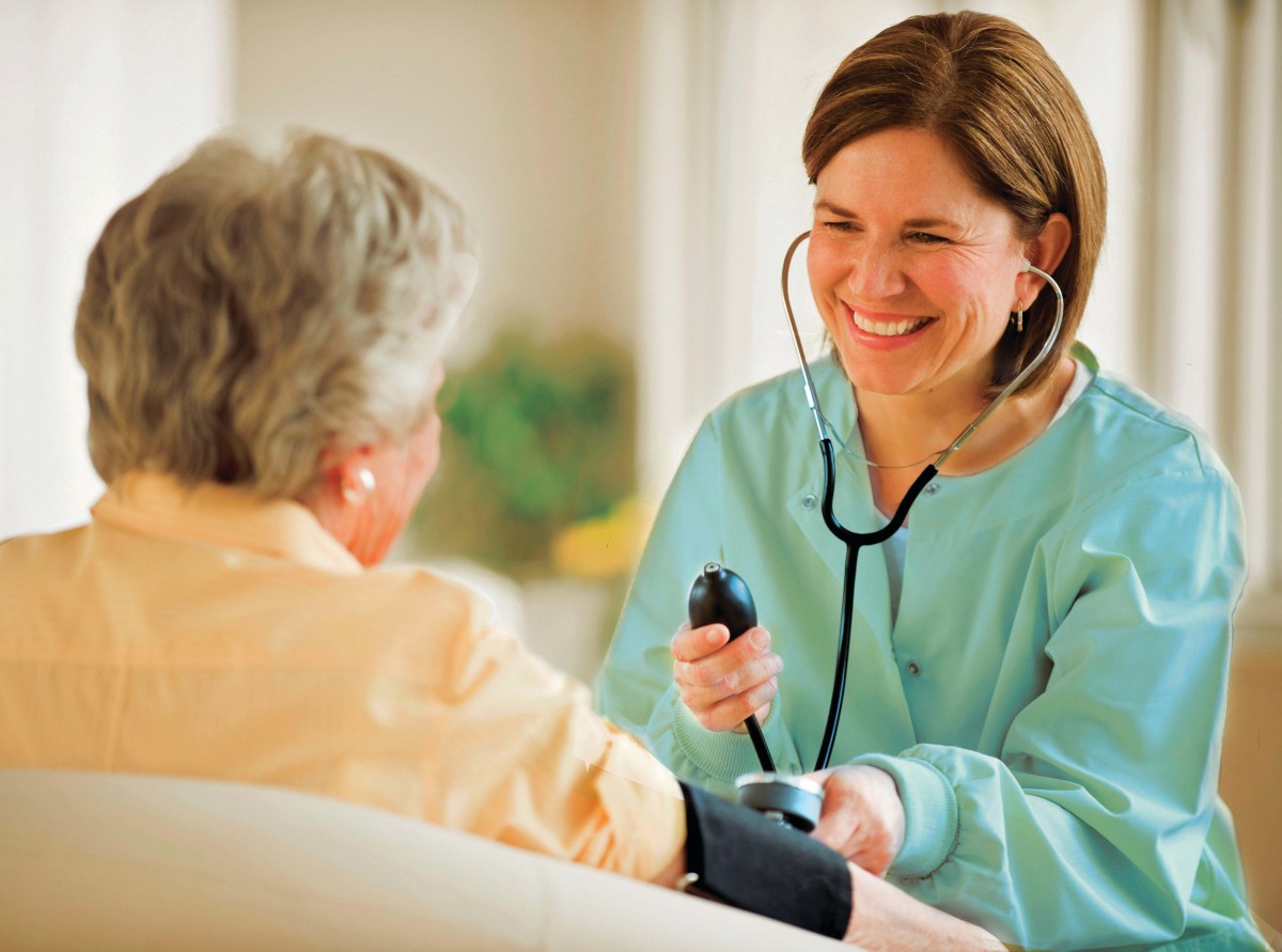 A nurse checks an elderly patient's blood pressure.