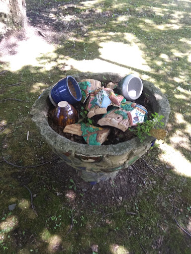 A trash can overflowing with various waste items in an outdoor setting.