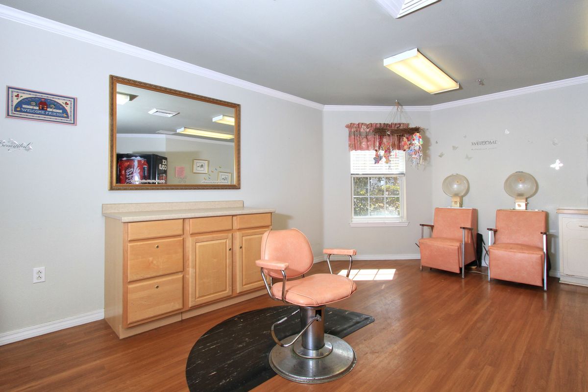 A well-lit hair salon interior featuring a styling chair, mirror, and wooden cabinetry.