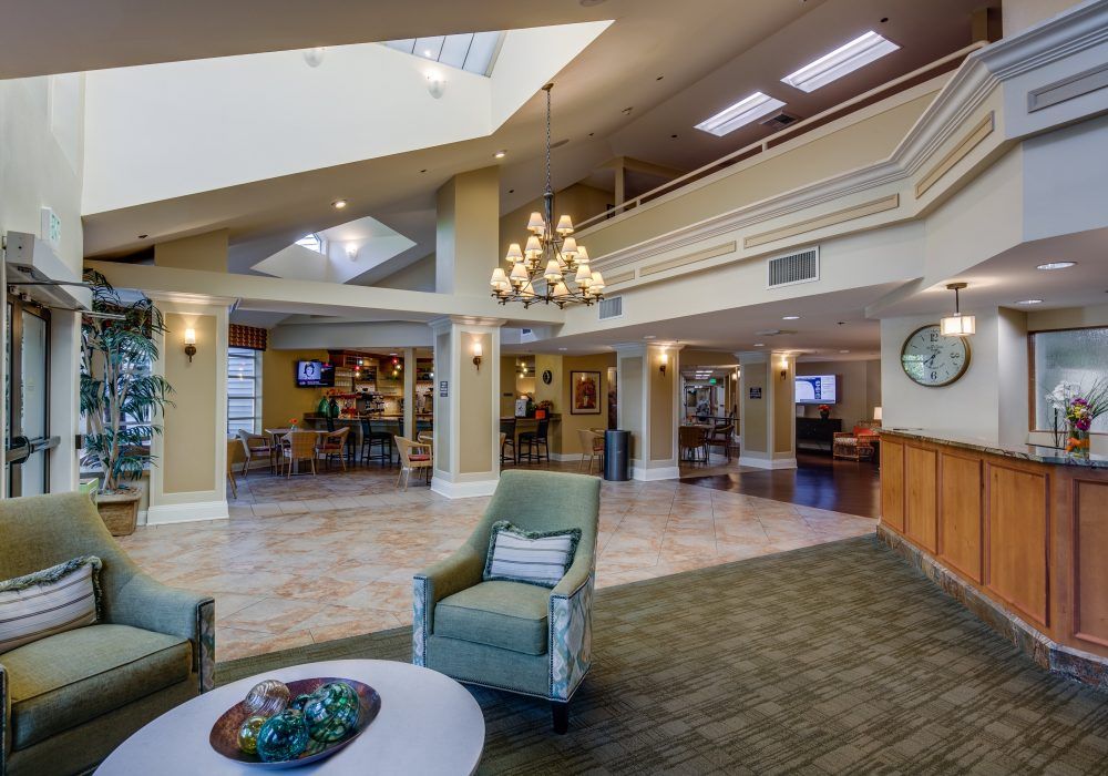 A spacious and well-lit lobby area with modern seating, a prominent chandelier, and a reception desk.