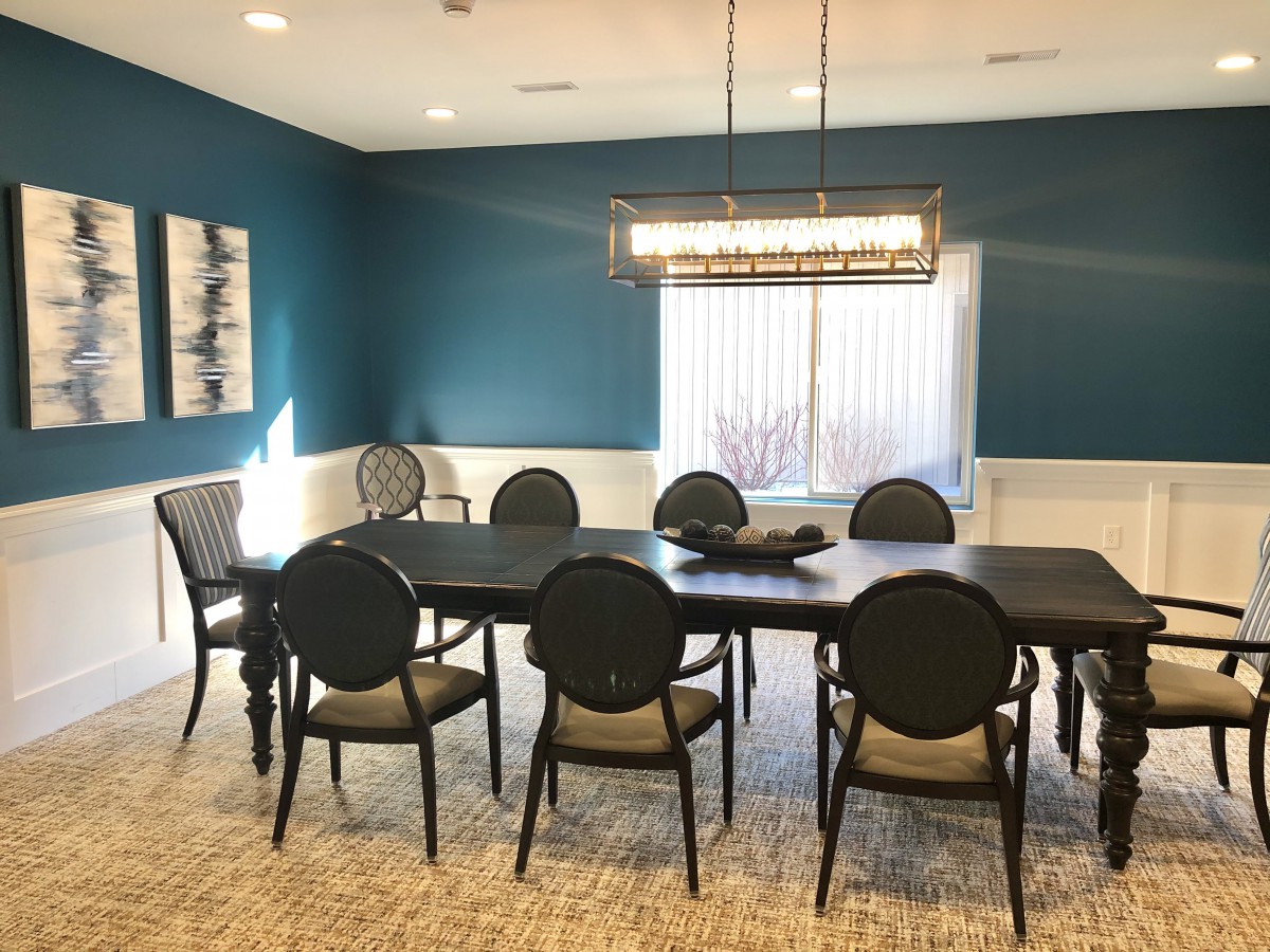 A modern dining room with blue walls, a large dining table, and elegant chairs.