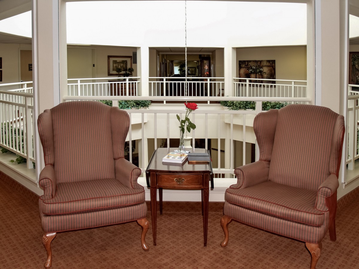 A cozy seating area with two armchairs and a table overlooking a balcony.