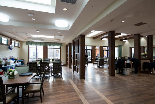A spacious and modern community dining area featuring wooden floors and ample natural light.