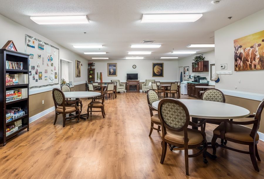 A spacious dining area with several round tables and chairs on a hardwood floor.