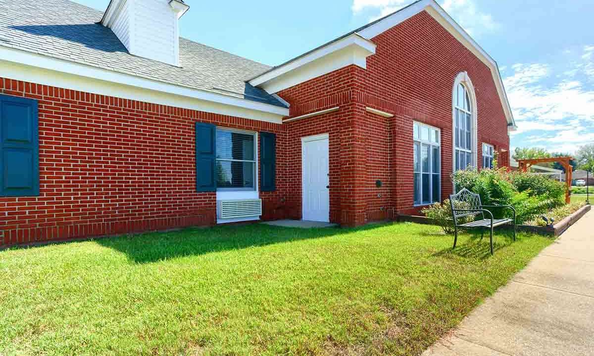 A brick building with large windows, a white door, and a neatly maintained lawn.