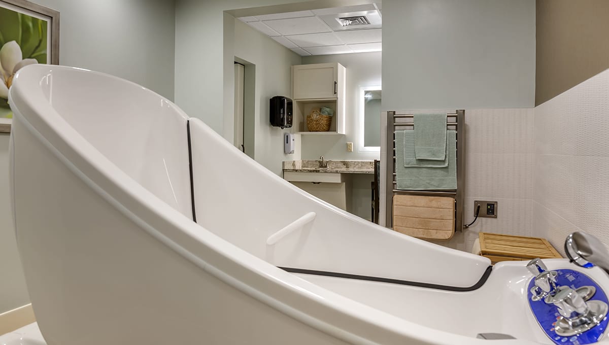 A modern bathroom with a large bathtub, sink area, and neatly arranged towels.
