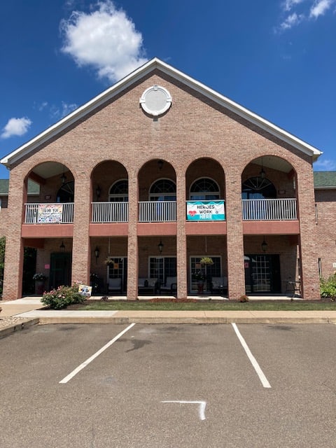 A two-story brick commercial building with arched windows and a parking lot in front.