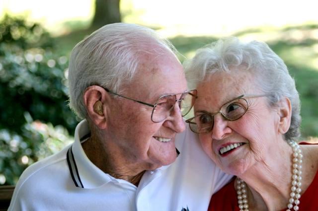 An elderly couple sharing a joyful moment outdoors.