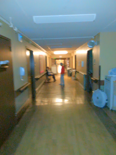 A view of a hospital corridor with soft lighting and people in the distance.