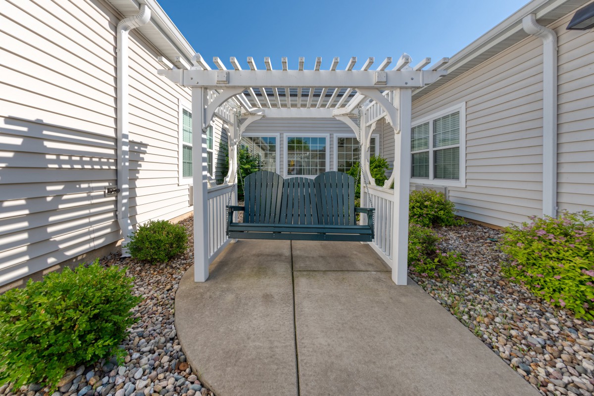 A charming outdoor space featuring a pergola with a swing in a neatly landscaped garden.