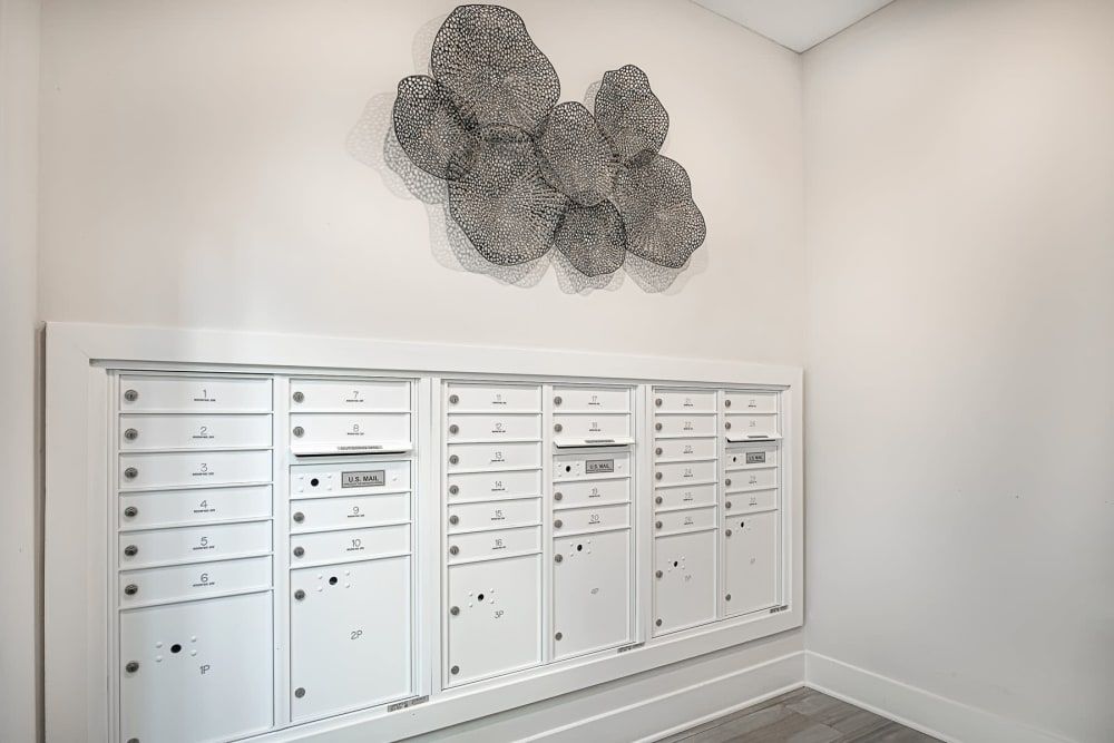 A modern interior featuring a set of white mailboxes with artistic wall decor above.