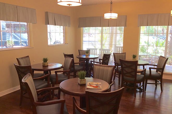 A cozy dining area with round tables and chairs, warmly lit by ceiling lights.