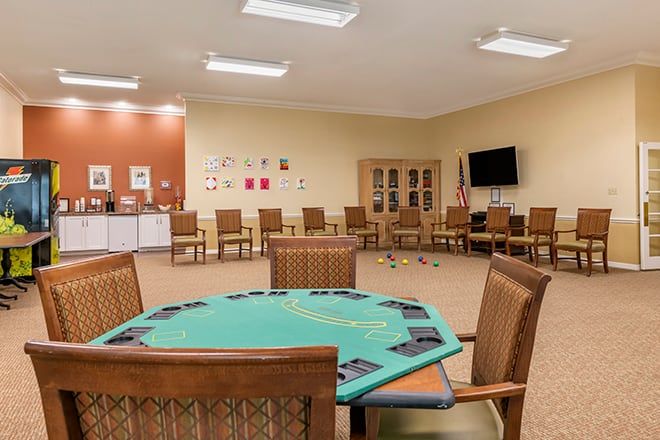 A spacious recreation room with a poker table and chairs, a television, and a cabinet.