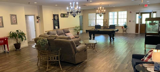 A spacious and elegantly decorated living room featuring a cozy sofa, stylish chandeliers, and a pool table.