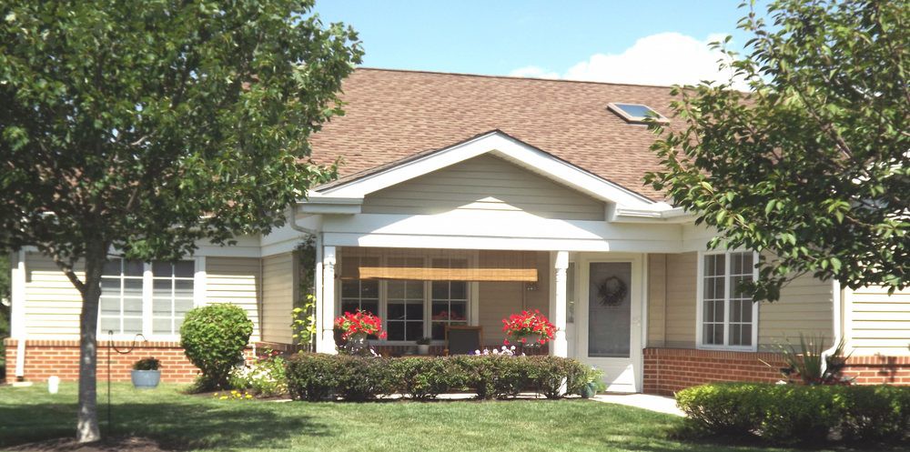 A charming suburban house with a well-kept front yard and flowers on the porch.