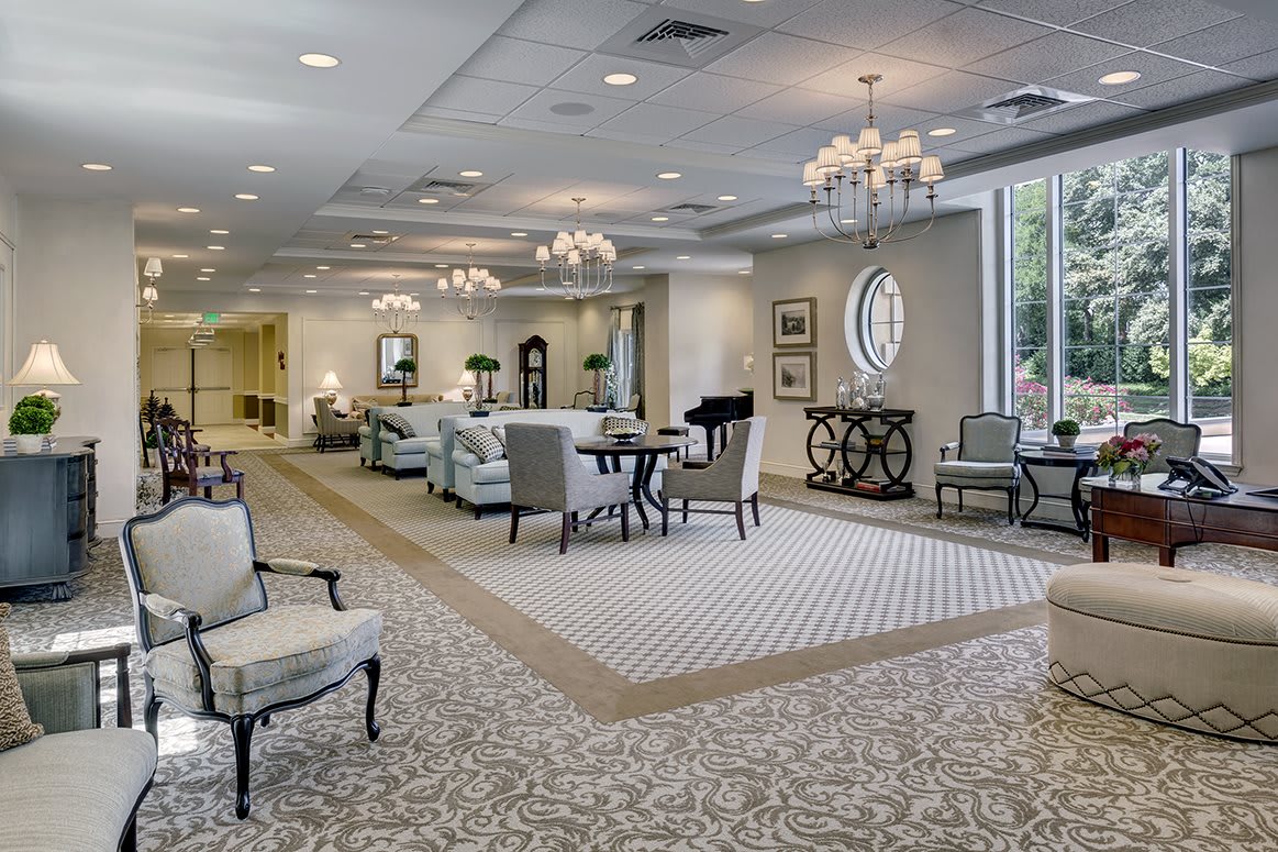 A spacious and elegantly designed lobby with comfortable seating, decorative mirrors, and chandeliers.
