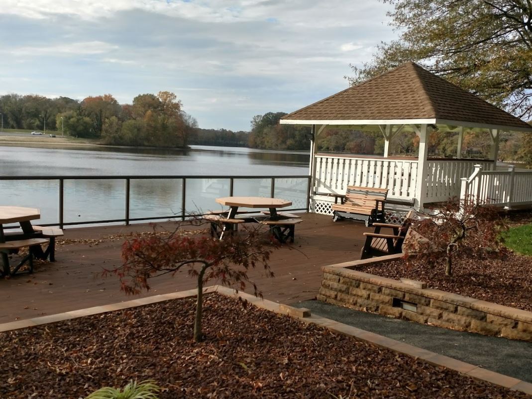 A peaceful lakeside view with a gazebo and seating area.