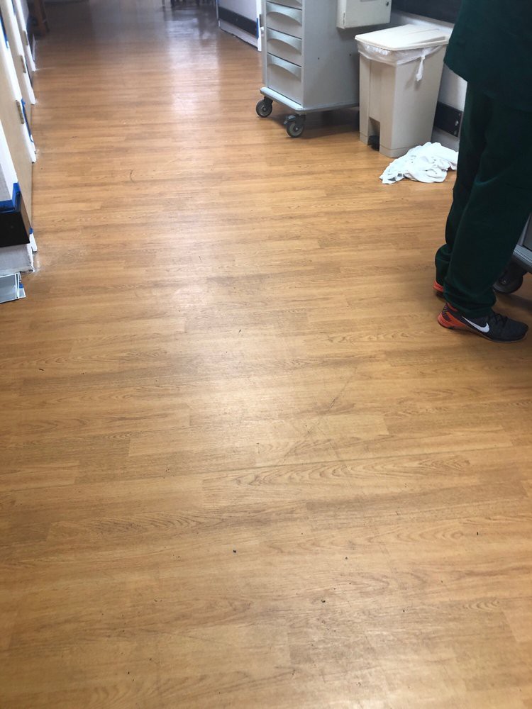 A wooden floor hallway with a person standing, visible from the waist down.