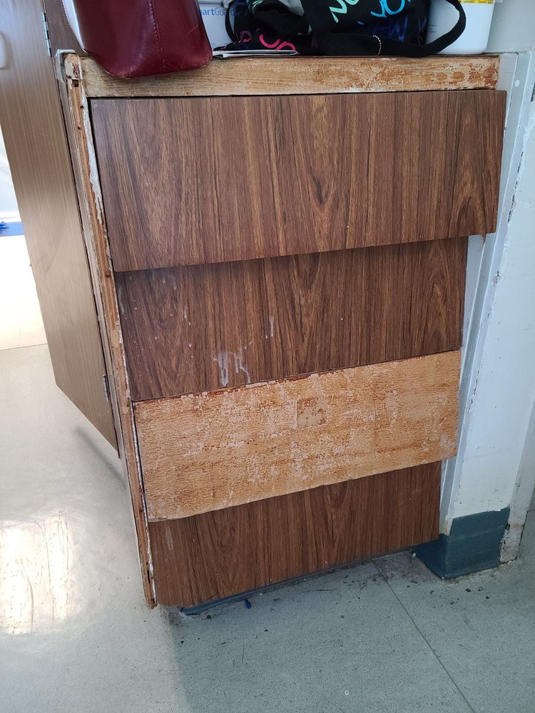 A wooden cabinet with three drawers, showing signs of wear.