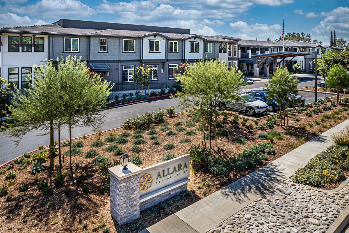 A modern residential building with landscaped surroundings and clear skies.