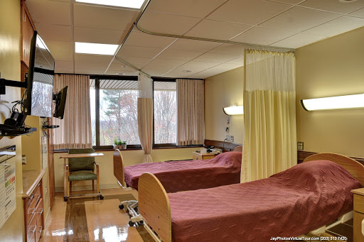 A view of a hospital patient room featuring two beds separated by curtains.