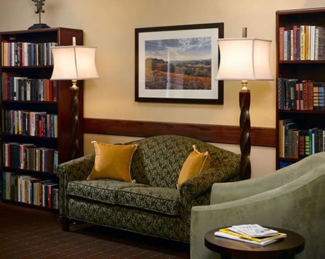 Cozy living room with a patterned sofa, standing lamps, and bookshelves.