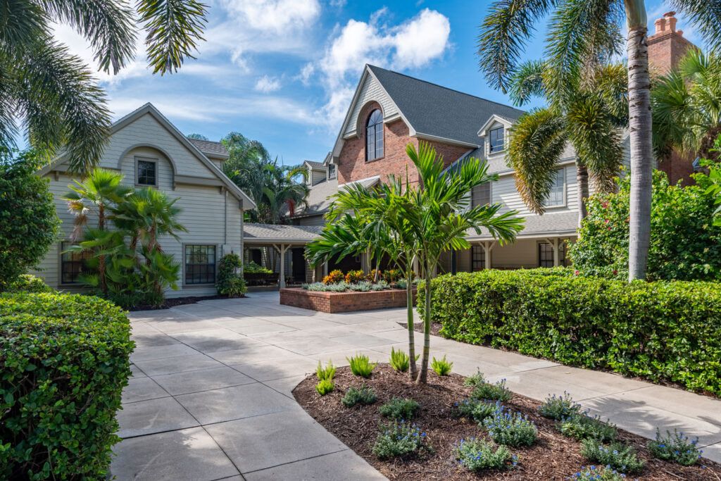 A beautiful residential house with a landscaped driveway and lush greenery under a blue sky.